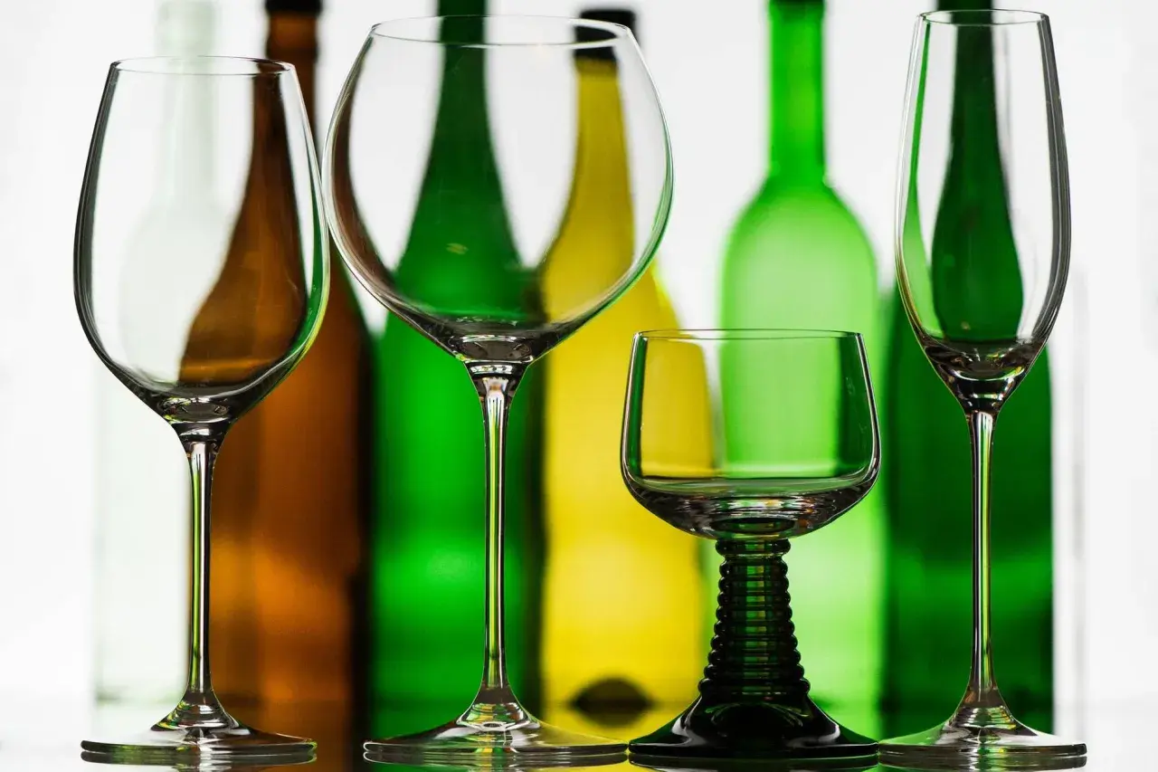 Leere Weingläser stehen vor bunten Flaschen. Die richtige rotwein temperatur ist entscheidend für den Genuss.
