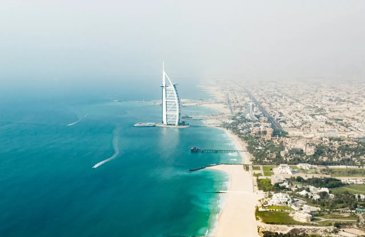 Widok z lotu ptaka na plaże w Dubaju, z charakterystycznym hotelem Burdż al-Arab i turkusową wodą.