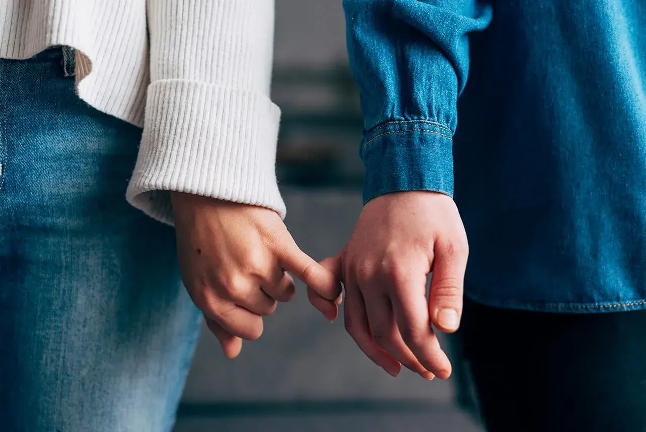 Due mani si stringono con il mignolo, simbolo di un legame che si rinnova dopo un periodo di **lasciarsi e riprendersi psicologia**.