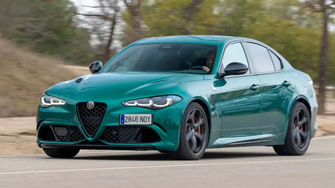 Un Alfa Romeo Giulia verde es conducido en una carretera, con el conductor visible al volante. Es una prueba del coche.