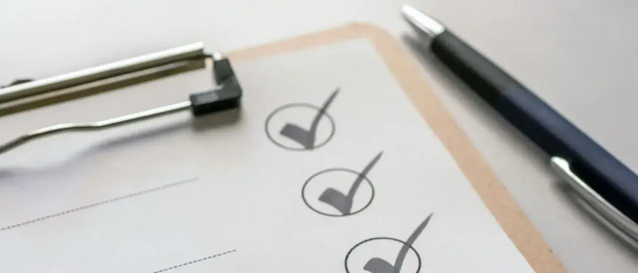 Klemmbrett mit Stift und abgehakten Punkten auf einer Checkliste.