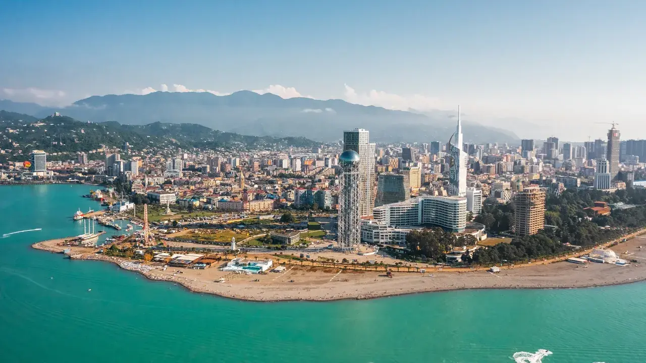 Widok na nowoczesne budynki Batumi i turkusowe morze. W tle góry, idealny batumi klimat do wypoczynku.