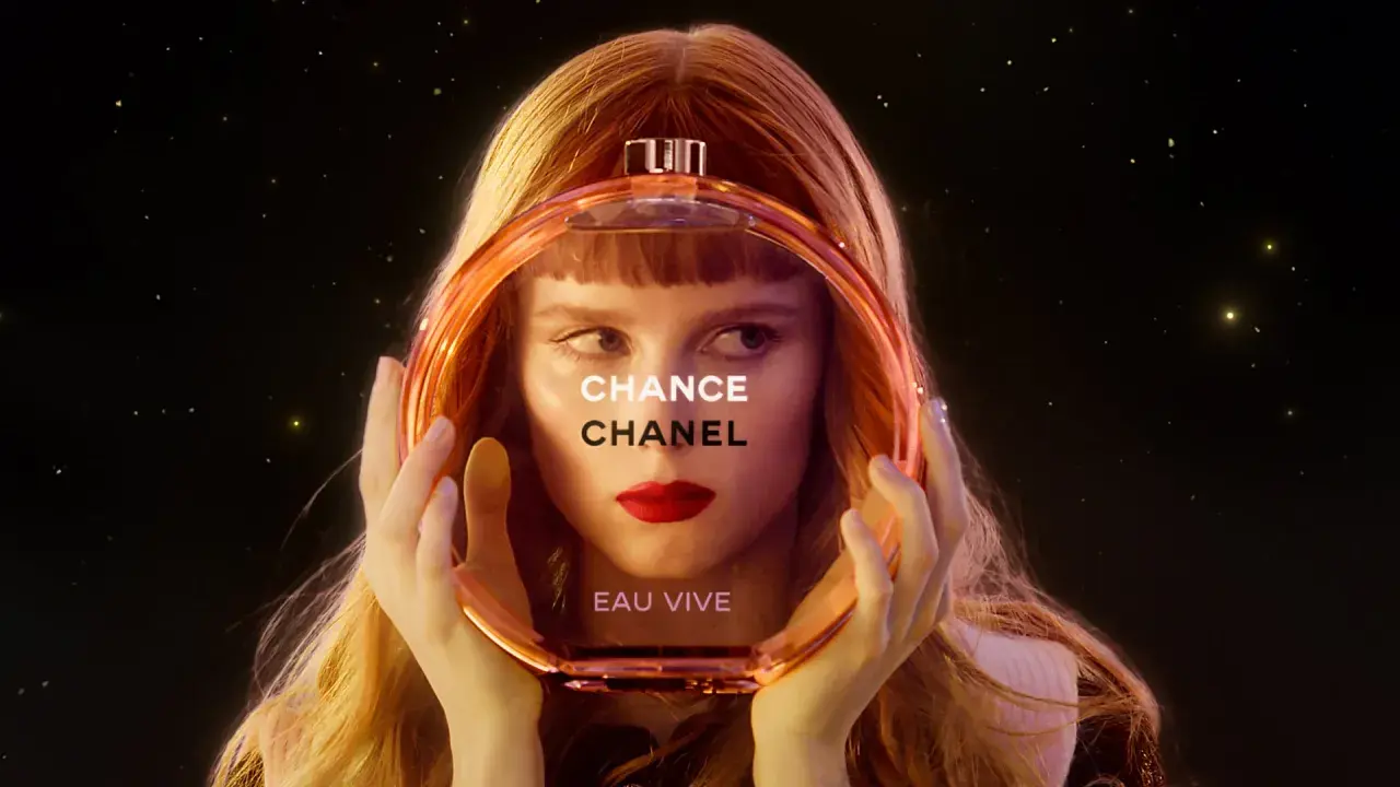 Kobieta z rudymi włosami trzyma okrągłą butelkę perfum Chanel Chance Eau Vive.