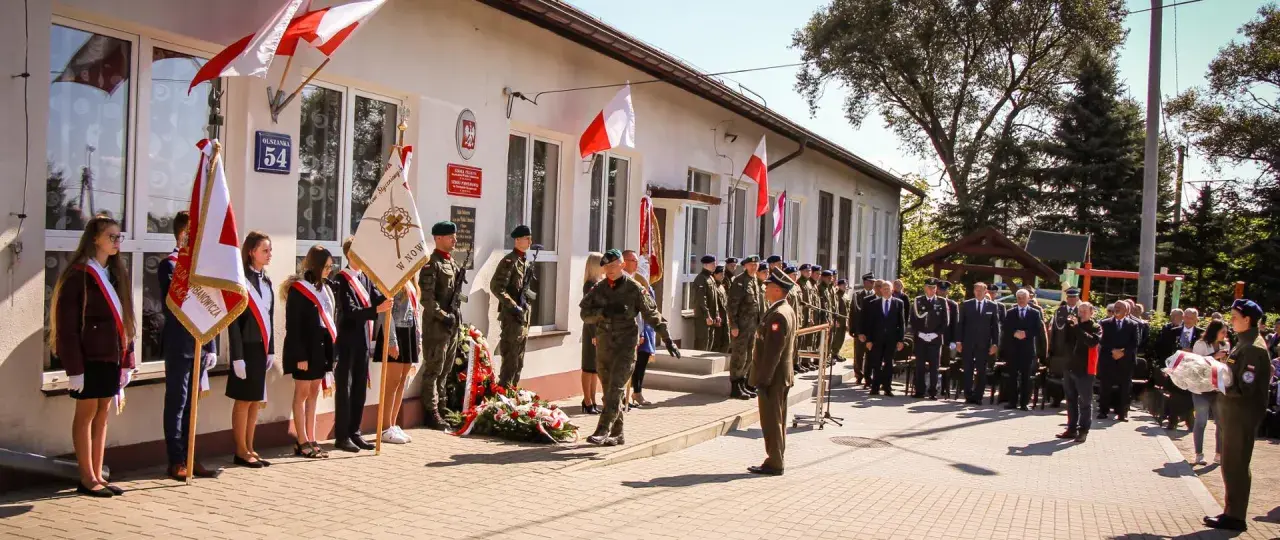 Uroczystość przed budynkiem szkoły z udziałem wojska, uczniów i gości.