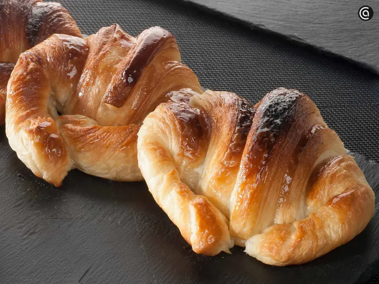 Deliciosos croissants dorados y brillantes, perfectos para aprender como hacer croissant casero.