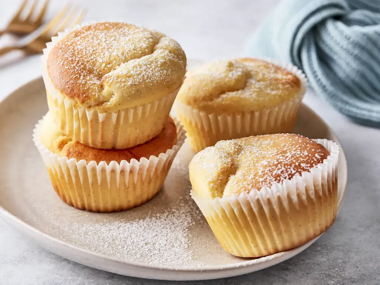 Saftige Muffins mit Quark, bestäubt mit Puderzucker, auf einem Teller arrangiert.