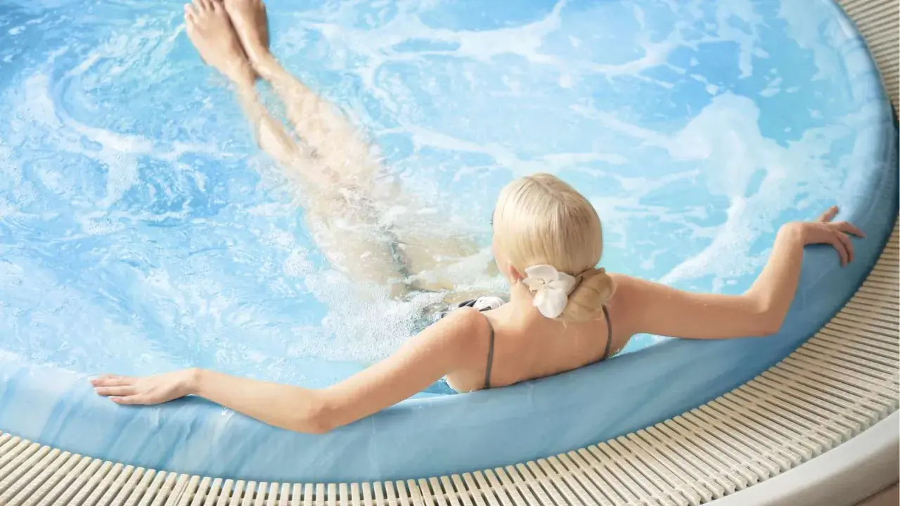 En gravid kvinna njuter av ett varmt bad i en jacuzzi, med benen uppsträckta i det bubblande vattnet.