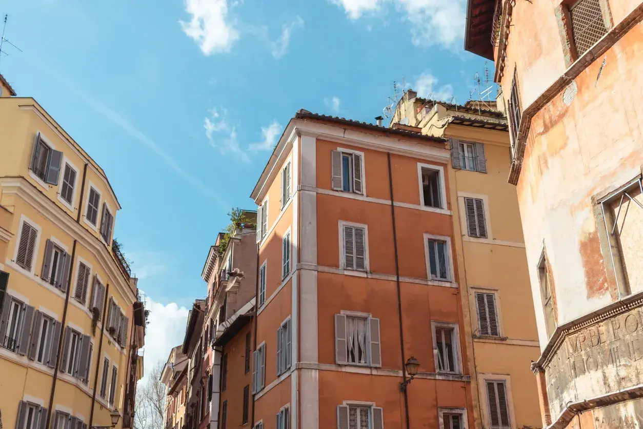 Edifici color pastello a Roma, con persiane chiuse. Il loro valore di un immobile inagibile è incerto, ma il fascino storico rimane.