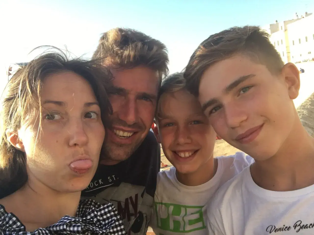 Famiglia in vacanza con ragazzi di 15 anni, sorrisi e sole.
