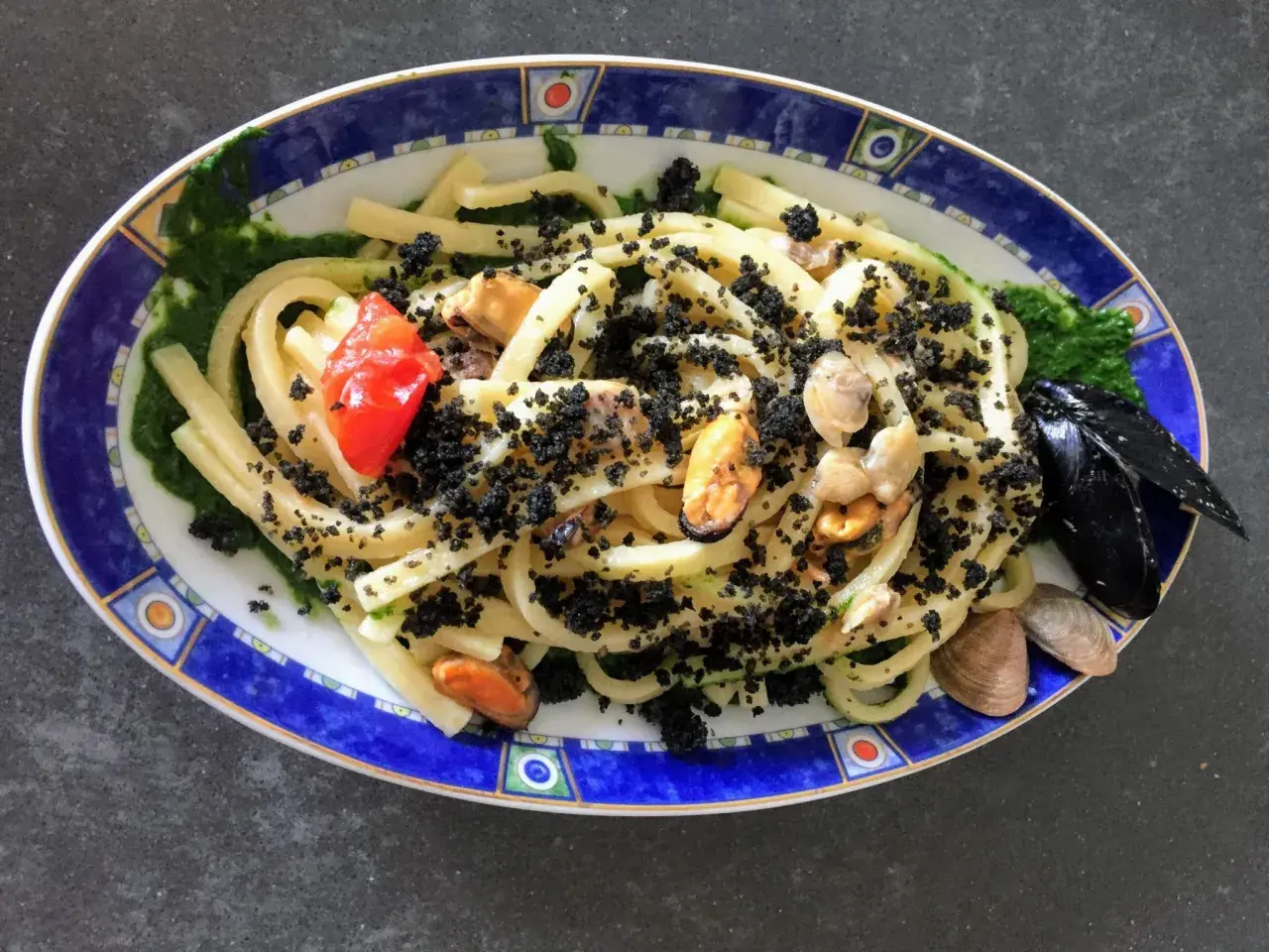 Scialatielli con cozze, pomodorini e una spolverata di pecorino grattugiato, su un letto di salsa verde.