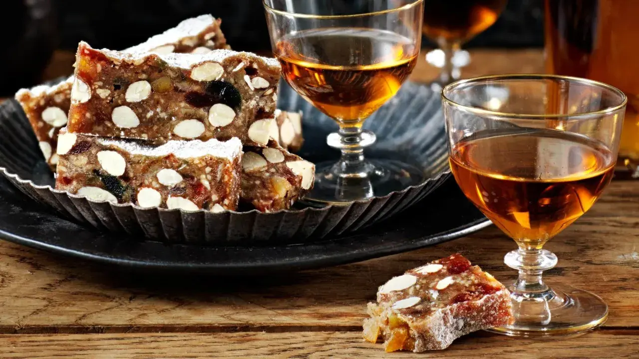 Panforte-bitar med mandlar och torkad frukt, pudrade med florsocker, serveras med ett glas gyllene likör. Ett härligt panforte recept att njuta av.