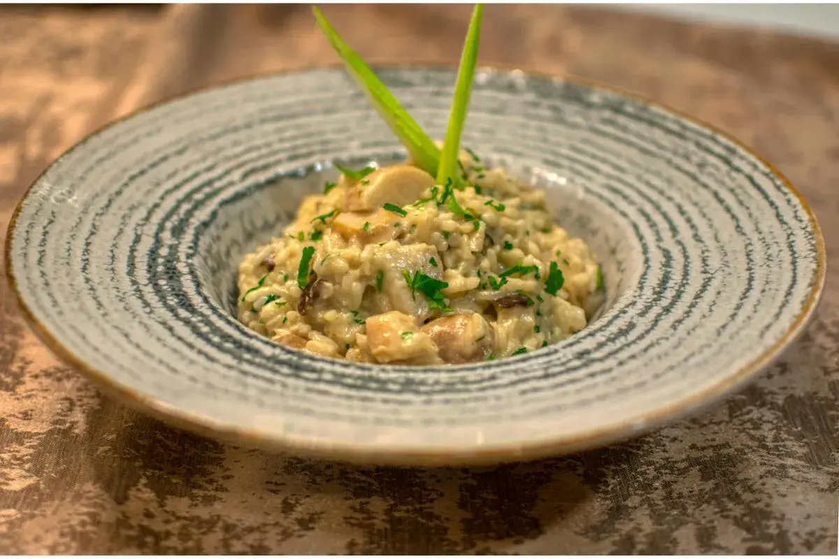 Un crémeux risotto champignon, parsemé de persil frais et garni d'une touche verte. Un délice pour les yeux et les papilles.
