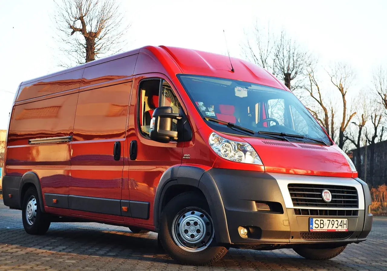 Czerwony Fiat Ducato Maxi zaparkowany na zewnątrz, gotowy do transportu.