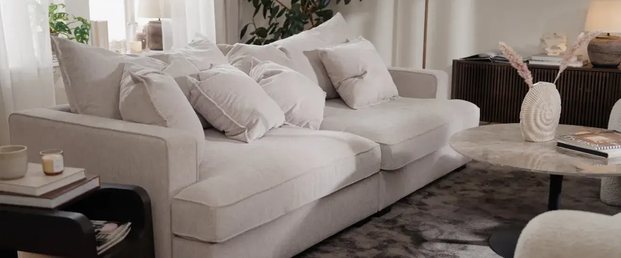 En ljus, fluffig soffa med många kuddar. Perfekt för att mysa i efter att du valt att impregnera soffan för extra skydd.