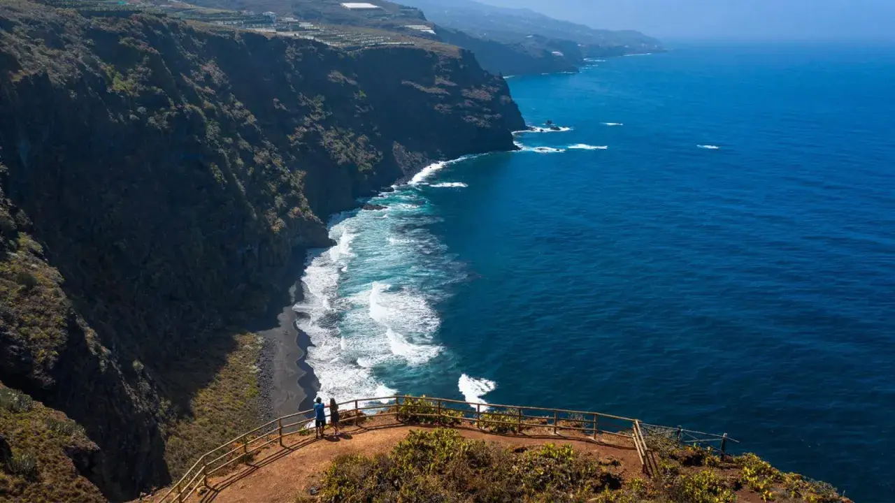 Pareja admira la playa de nogales, una costa volcánica de arena negra bañada por el azul intenso del océano.