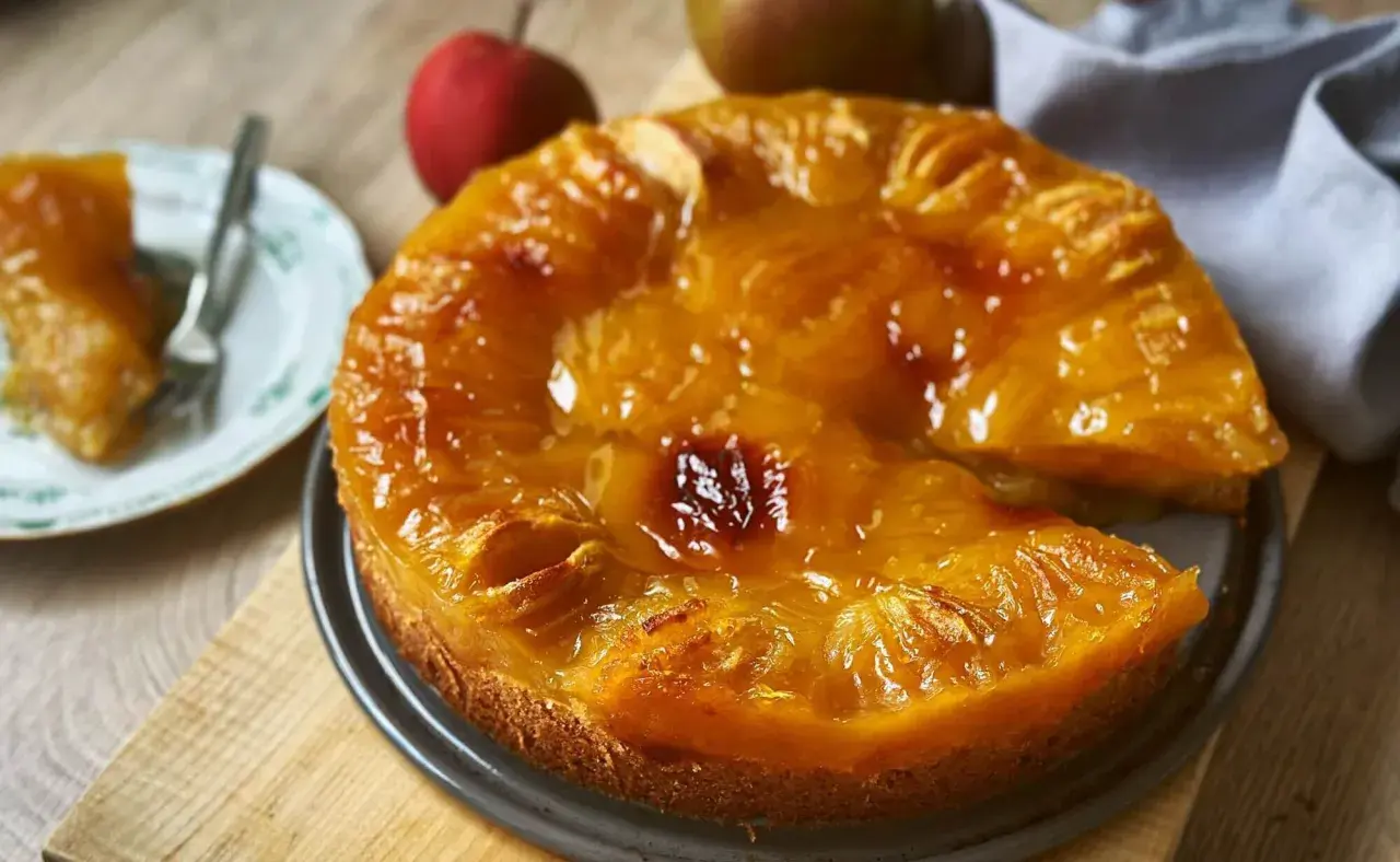 Saftiger Obstkuchen aus der Springform, mit karamellisierten Früchten und einem Stück auf einem Teller. Ein köstliches Obstkuchen Rezept.