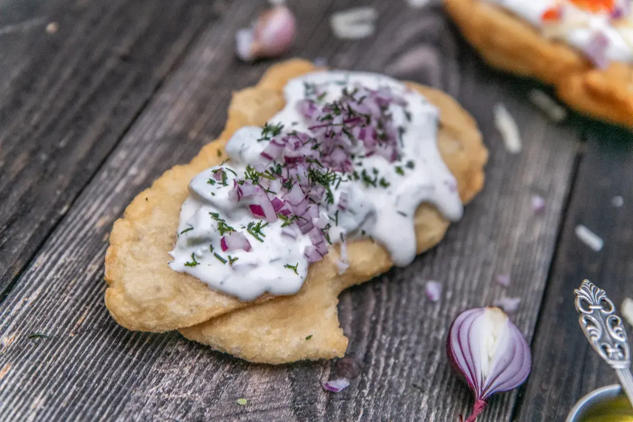 En friterad langos med gräddfil, hackad rödlök och dill. Perfekt för ett snabbt langos recept.