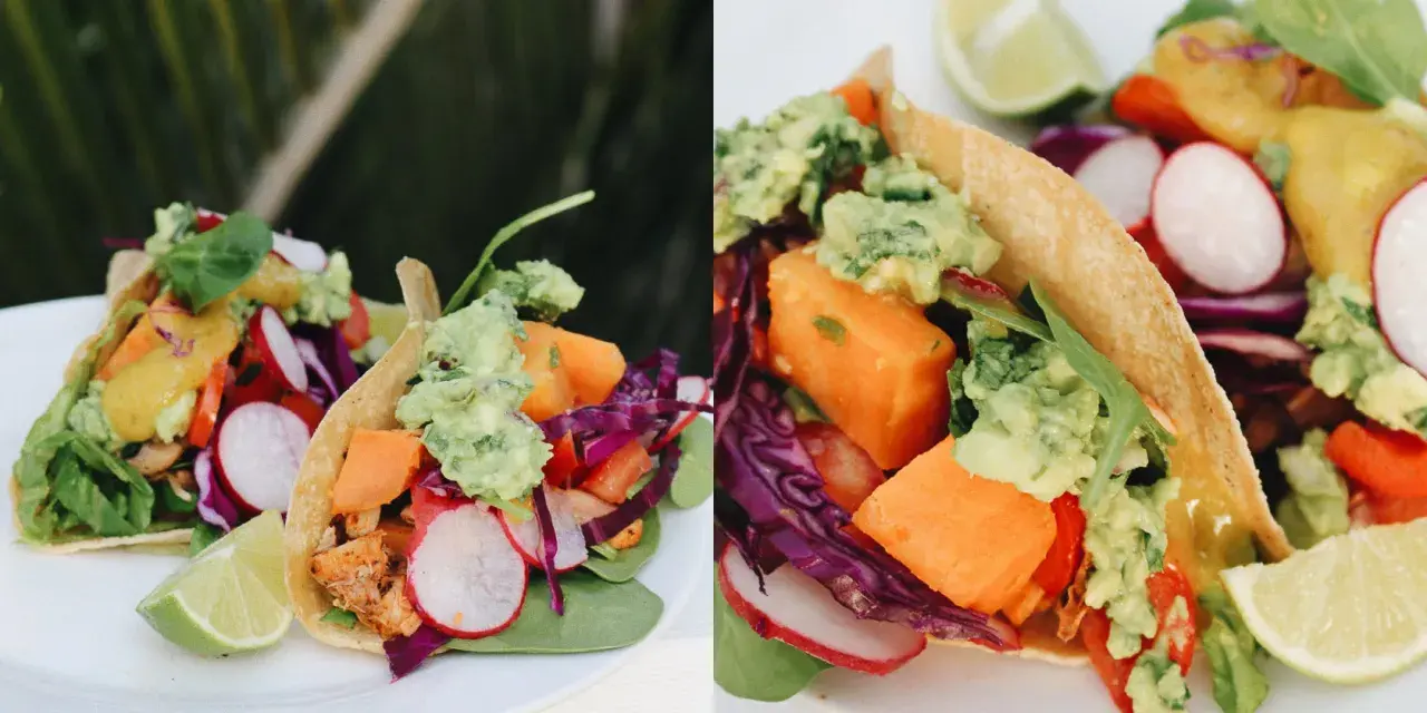 Deliciosos tacos vegetarianos con aguacate, camote, rábano y col morada, servidos con gajos de limón.
