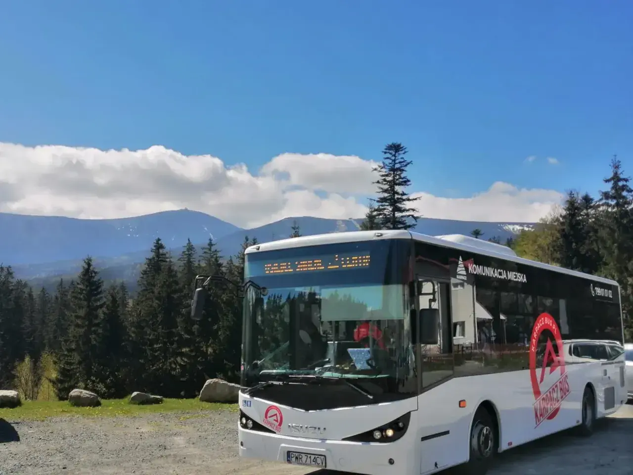 Biały autobus komunikacji miejskiej "Karpacz Bus" na tle gór i lasu. Idealny transport busem na górskie wycieczki.