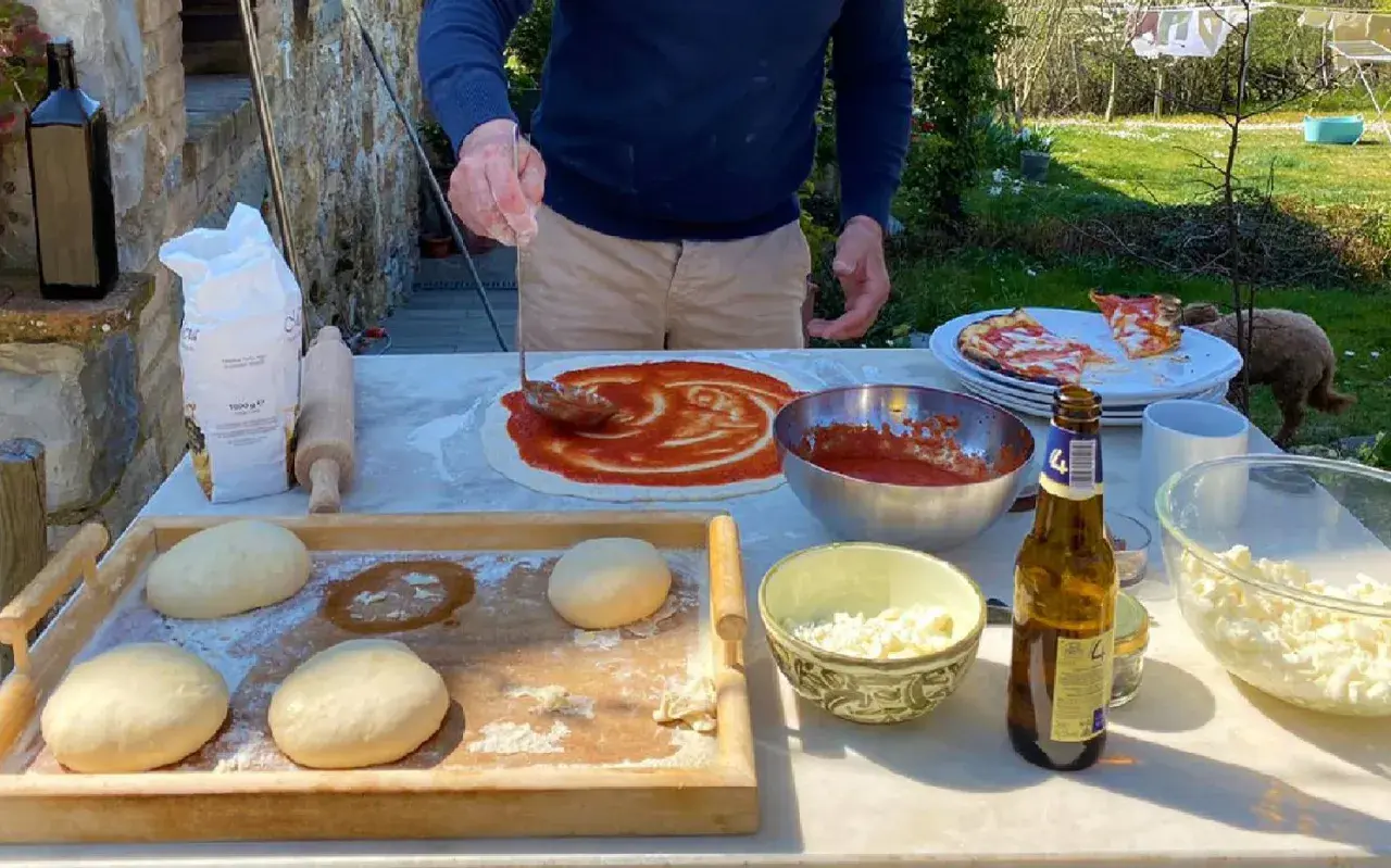Przygotowanie pizzy w słonecznym Chianti, Włochy. Ciasto, sos pomidorowy i ser czekają na pieczenie.