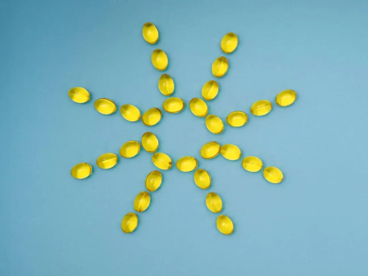 Gelbe Kapseln bilden eine Sonne, die gegen Winterdepression hilft. Vitamin D für mehr Licht.