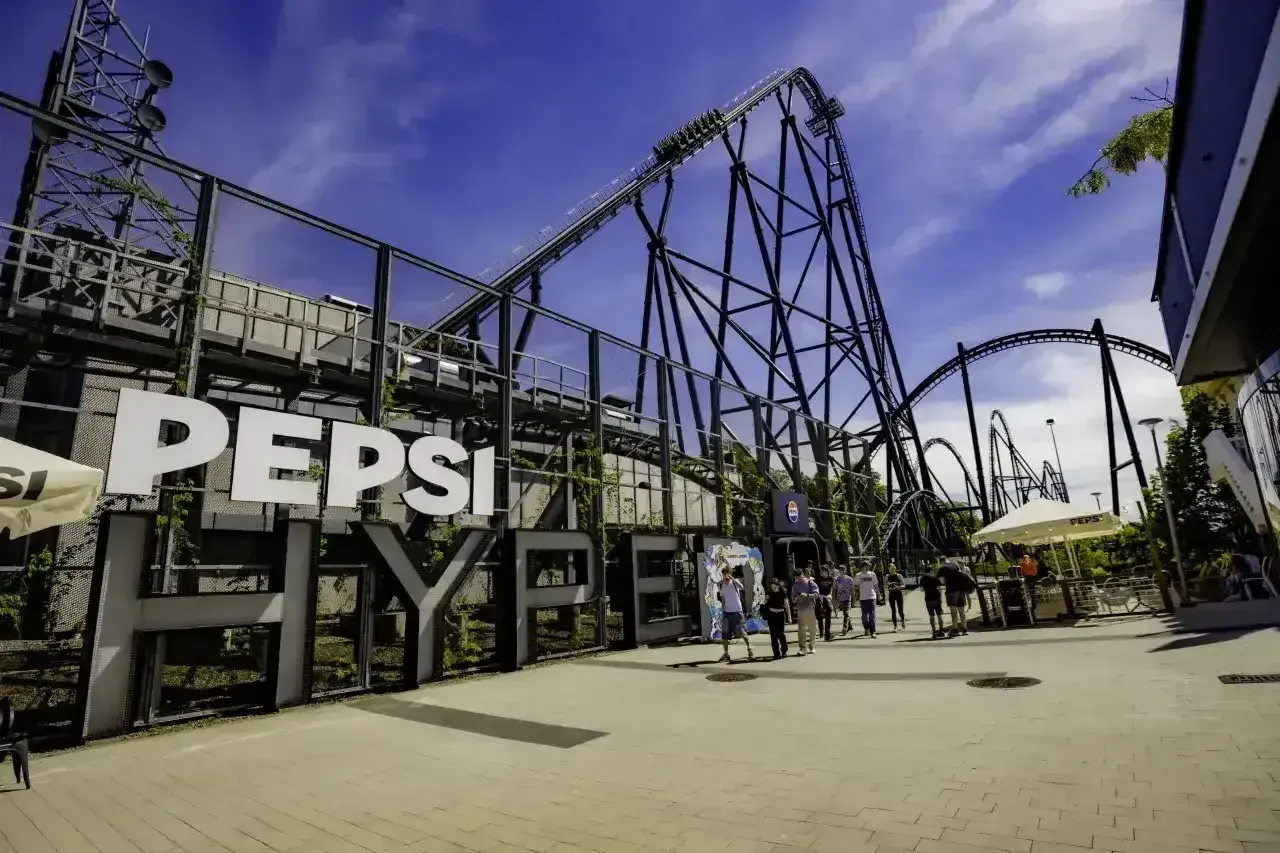 Energylandia opinie: ogromna kolejka górska Pepsi z ludźmi w tle.