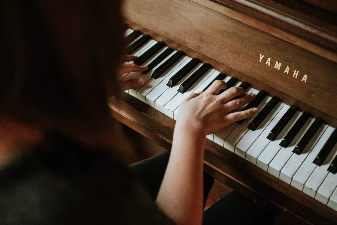 Dłonie dorosłego ćwiczą naukę gry na pianinie Yamaha.