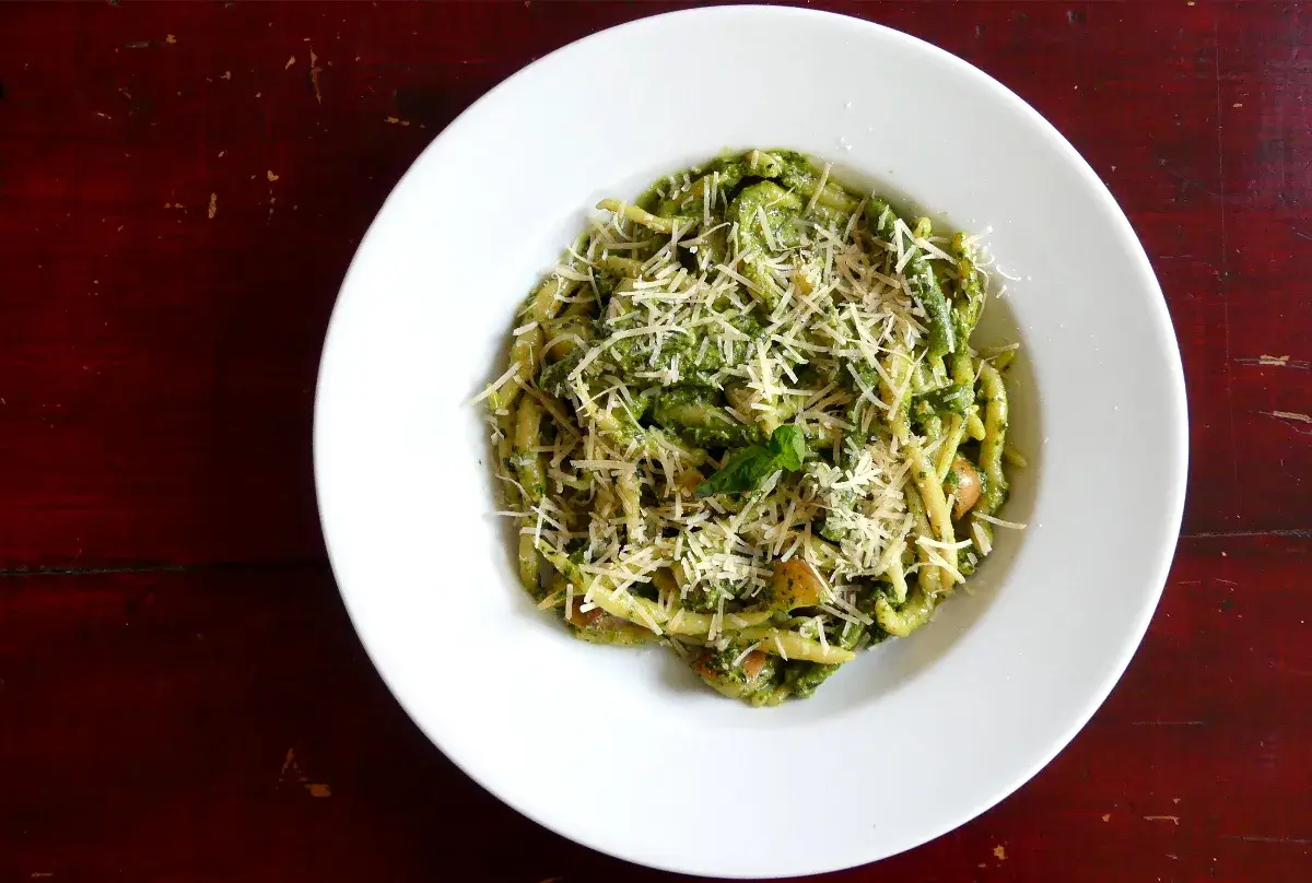 Assiette de trofie au pesto, garnie de parmesan râpé. Une recette italienne savoureuse et colorée.