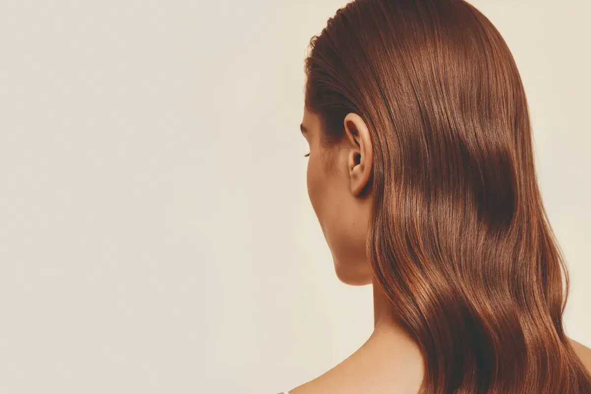 Cabello castaño brillante con un volumen envidiable, cayendo en ondas suaves sobre el hombro.