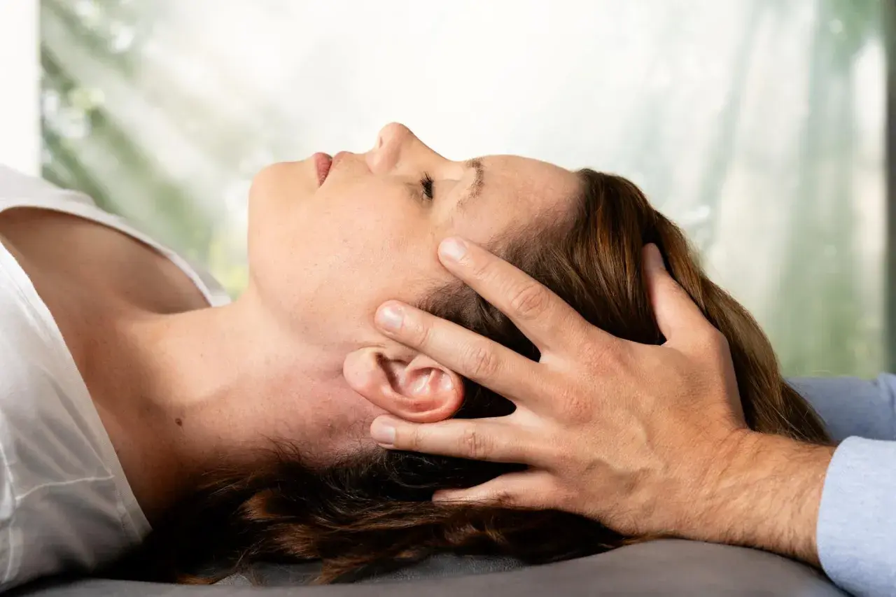 Osteopathie-Behandlung am Kopf, die den Nervus vagus stimuliert. Sanfte Berührung zur Entspannung.
