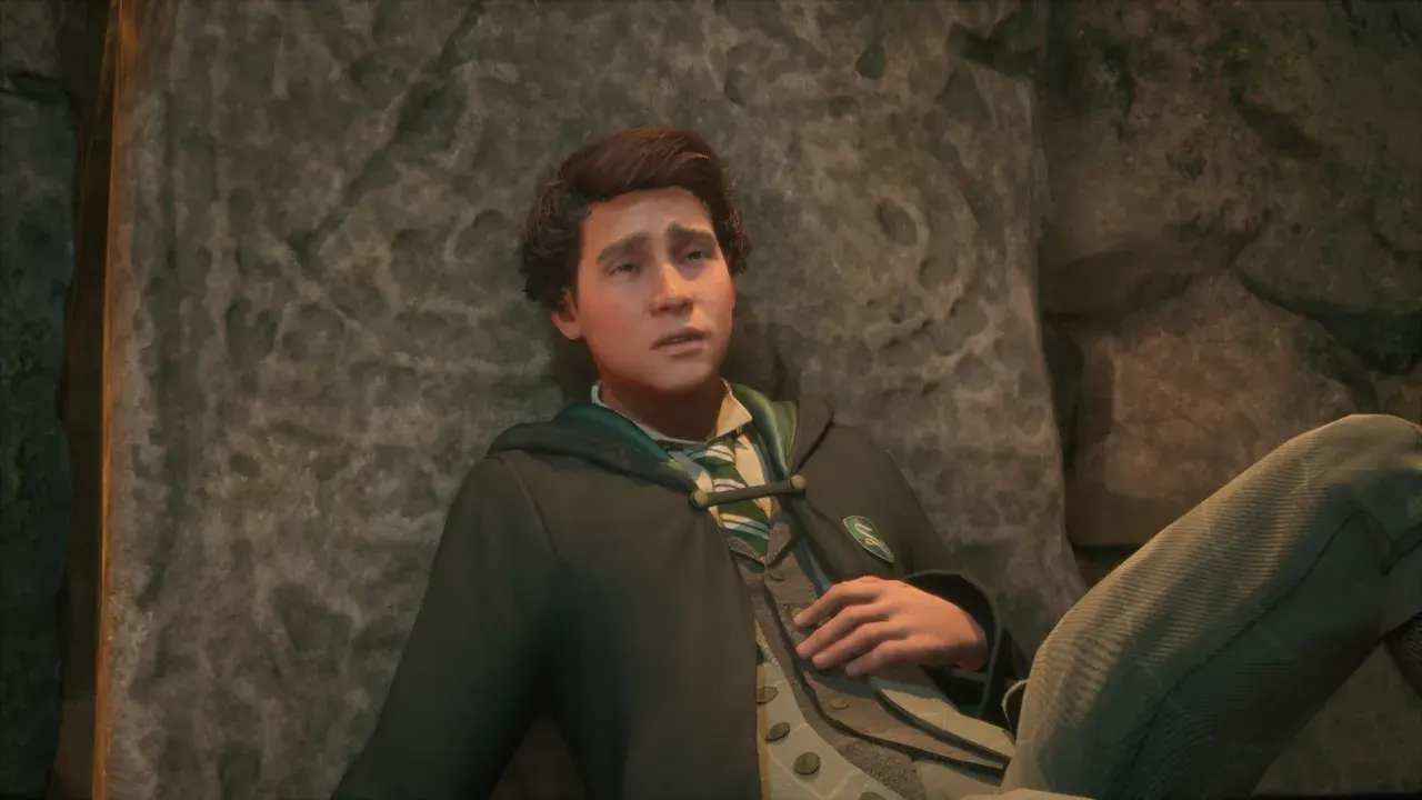 Zamyślony Sebastian z Hogwarts Legacy opiera się o kamień, w szacie Slytherinu.