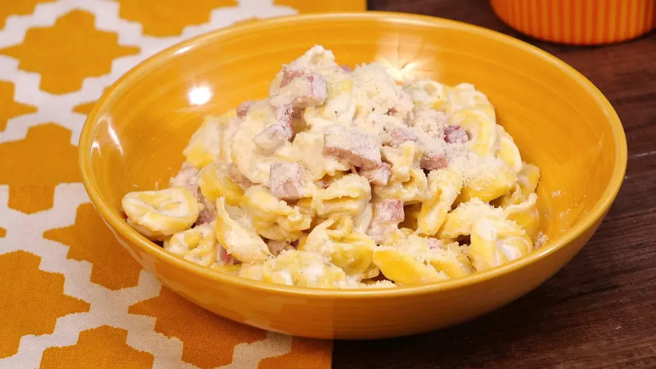 Tortellini panna e prosciutto, un piatto cremoso e saporito, servito in una ciotola gialla.