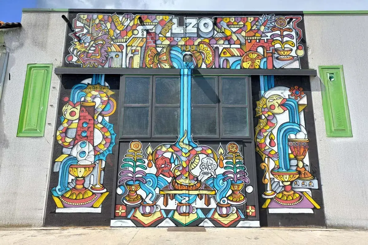 Mural colorato con il nome "LZO Brewery" in alto, raffigurante creature fantastiche, cascate e simboli.
