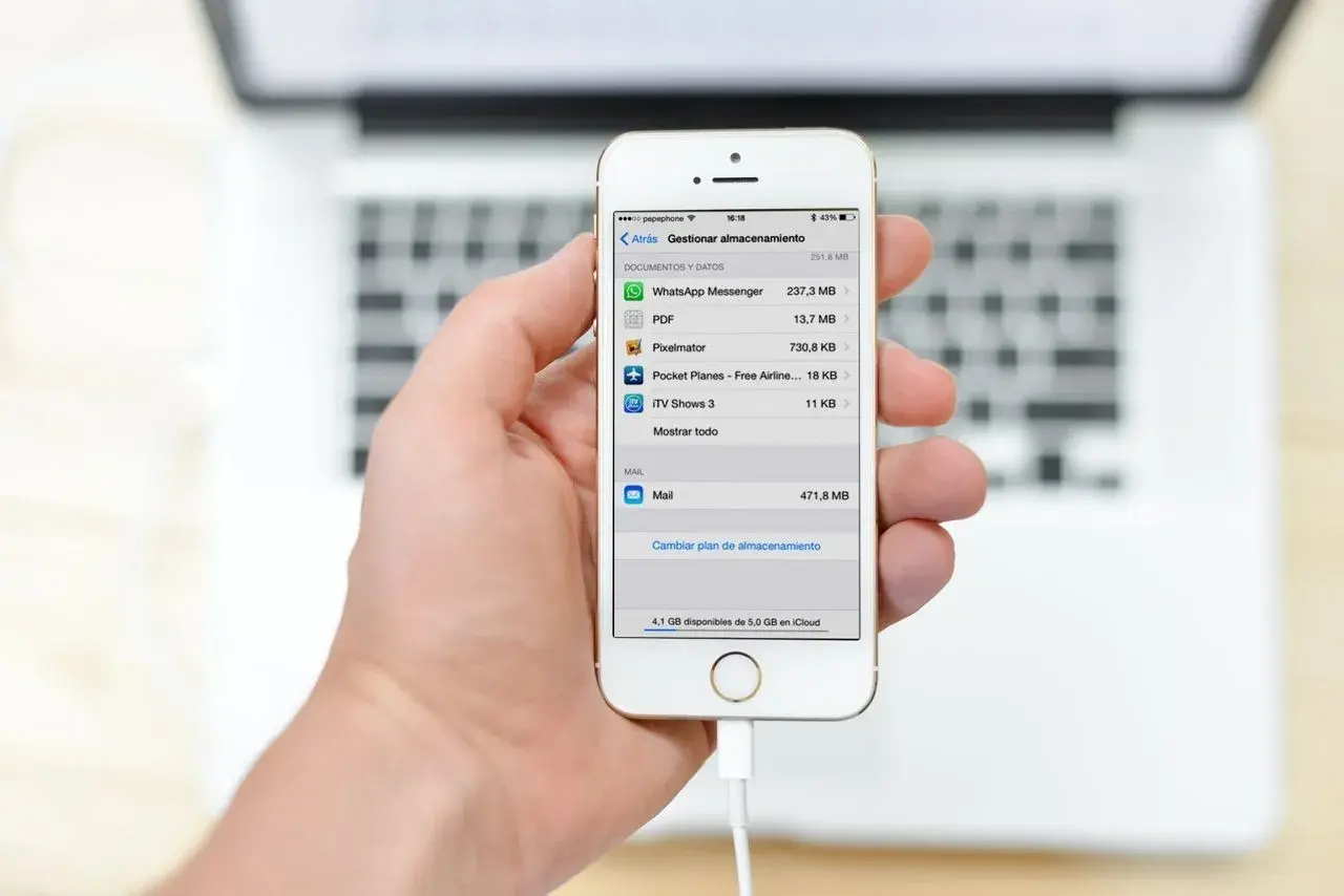 Mano sujetando un iPhone mostrando la gestión de almacenamiento, útil para la copia de seguridad iPhone.