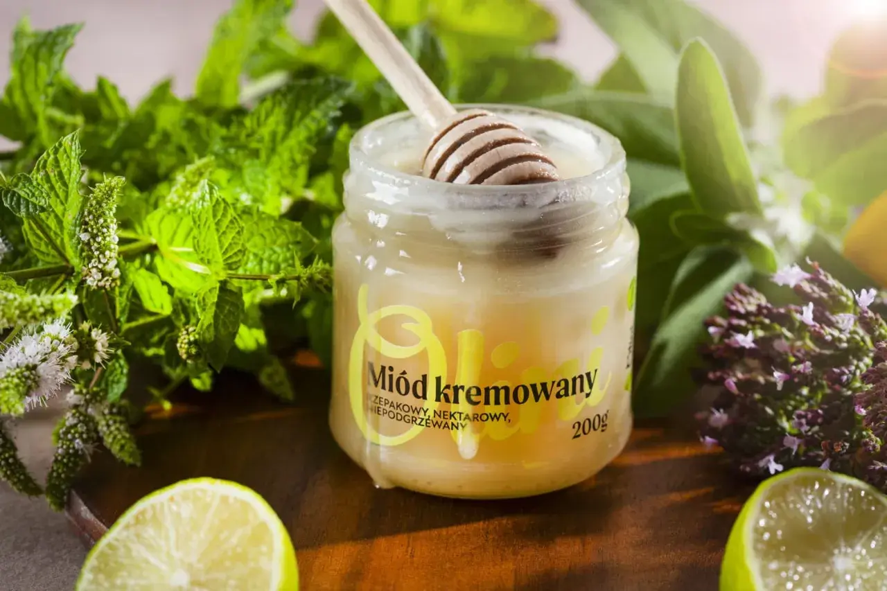 Słoik z miodem kremowanym, drewniana łyżka, świeża mięta, limonka i zioła. Idealny dodatek do herbaty.