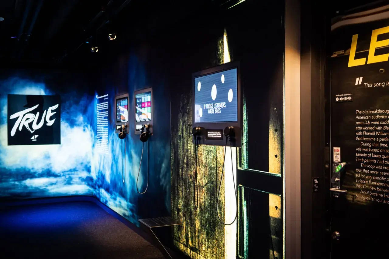 Utställning på Avicii museum med skärmar och hörlurar. En skärm visar texten "IF THOSE LISTENERS WERE EGGS".
