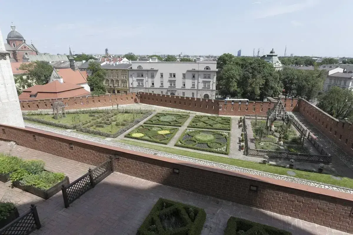 Krakowski ogród z geometrycznymi rabatami i architekturą, przypominający o dawnych czakramach w Polsce.