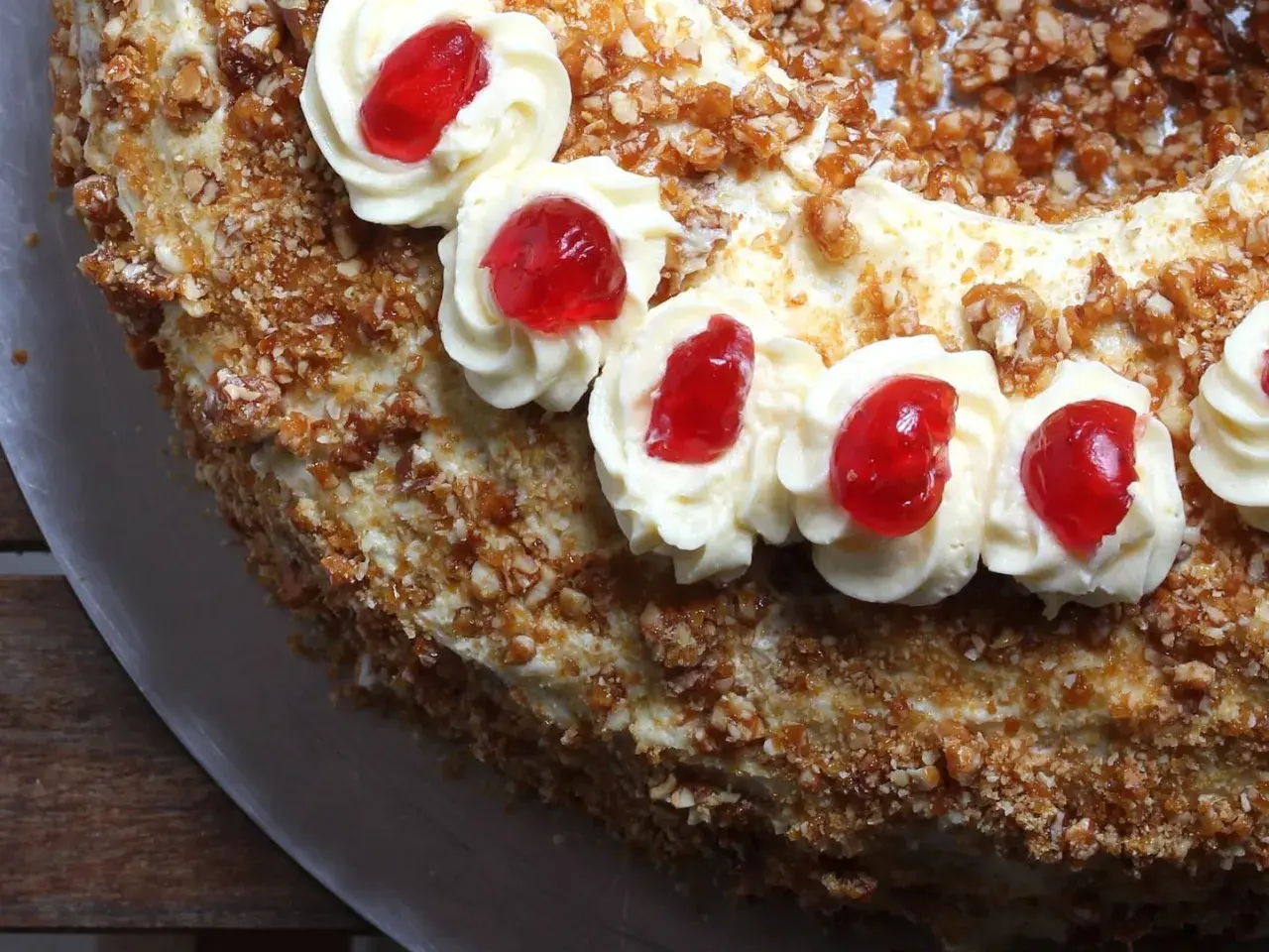 Ein köstlicher Frankfurter Kranz mit Buttercreme-Tupfern und roten Kirschen, umhüllt von knusprigen Mandelsplittern.