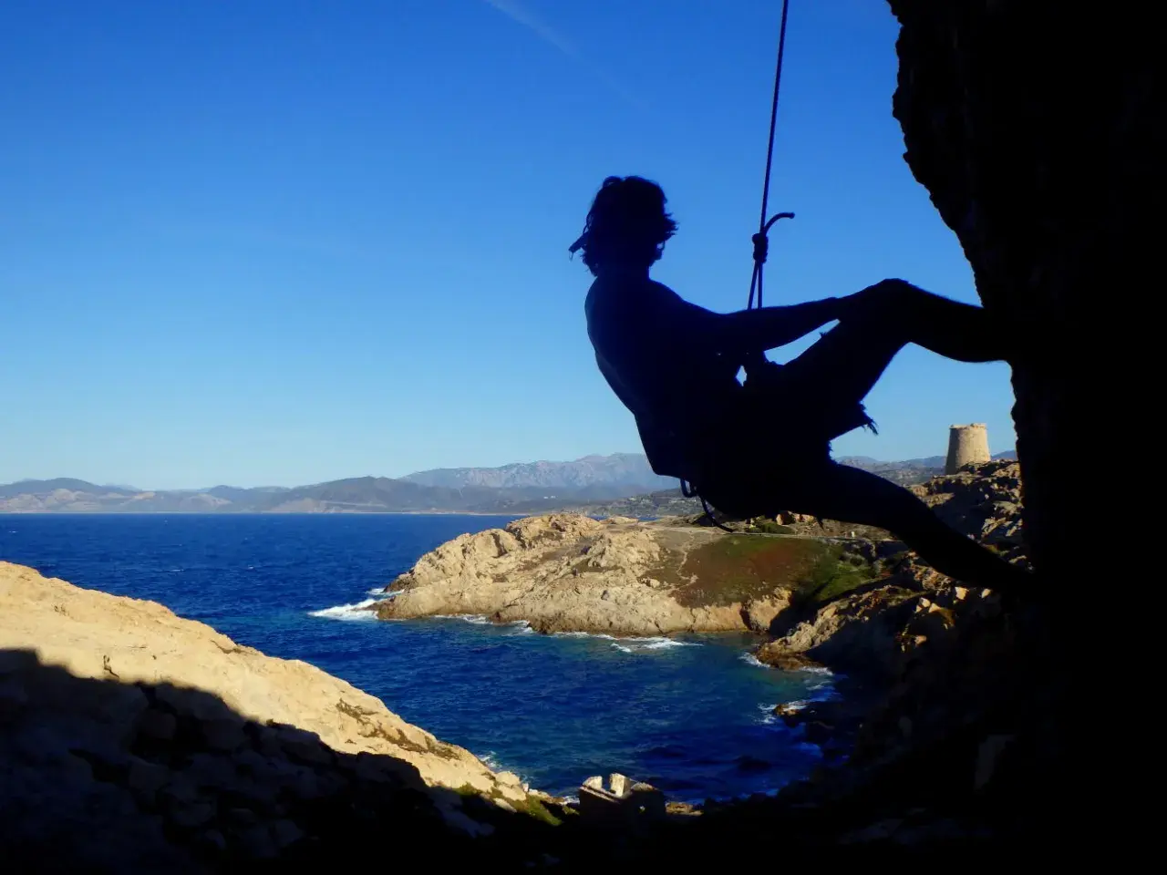 Silhouette eines Kletterers vor der Küste Korsikas. Ein Abenteuer beim Klettern auf Korsika.