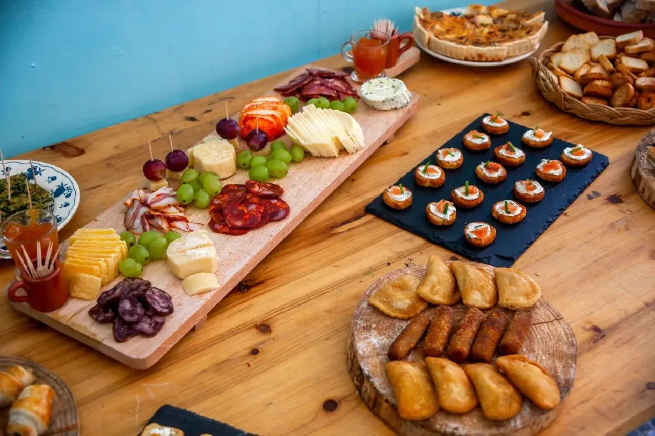 Un buffet champêtre gourmand : planches de charcuterie, fromages, raisins, mini-quiches et toasts saumon.