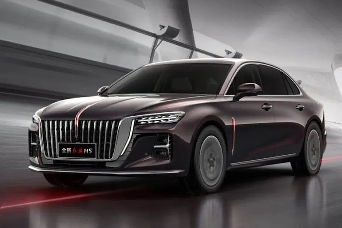 Elegancki, ciemnofioletowy Hongqi H5 z charakterystycznym grillem i czerwonym pasem na masce, poruszający się po nowoczesnej drodze.