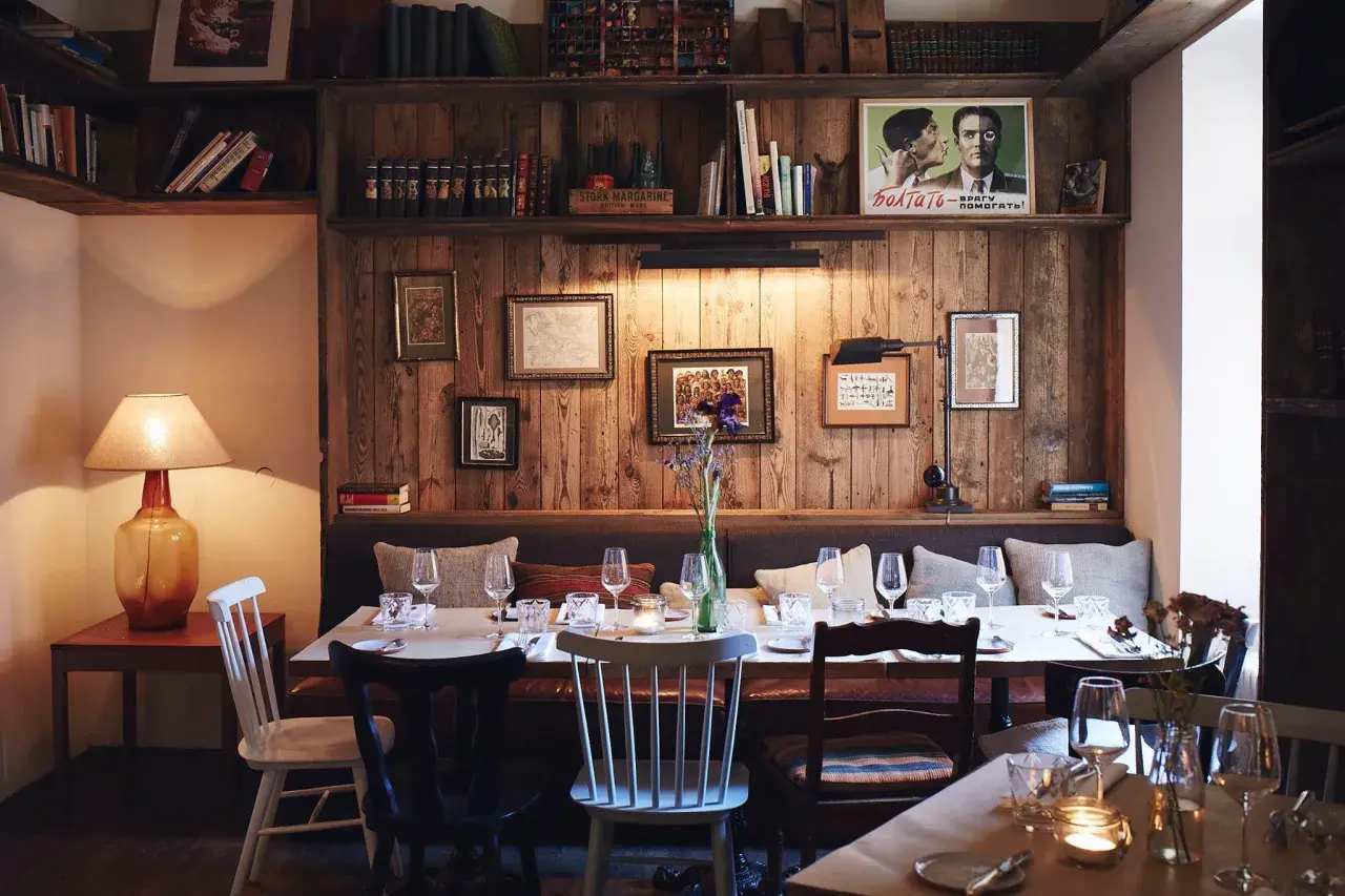 Gemütliche Atmosphäre in einem der besonderen Restaurants Berlins. Holzwände, Bücherregale und ein gedeckter Tisch laden zum Verweilen ein.