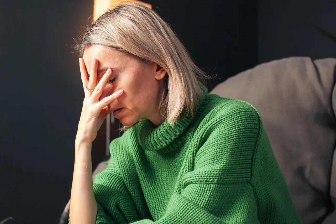 Donna con la mano sulla fronte, visibilmente provata. Un'immagine che evoca la lotta contro ansia e depressione, e la ricerca di come uscirne.