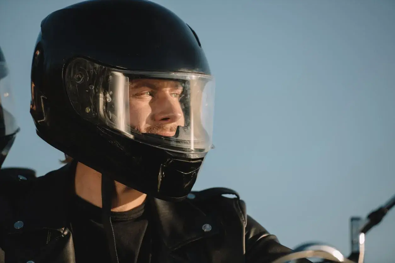 Hombre con casco de moto negro, listo para la aventura. Su mirada refleja la libertad y la seguridad que ofrece la homologación DOT.