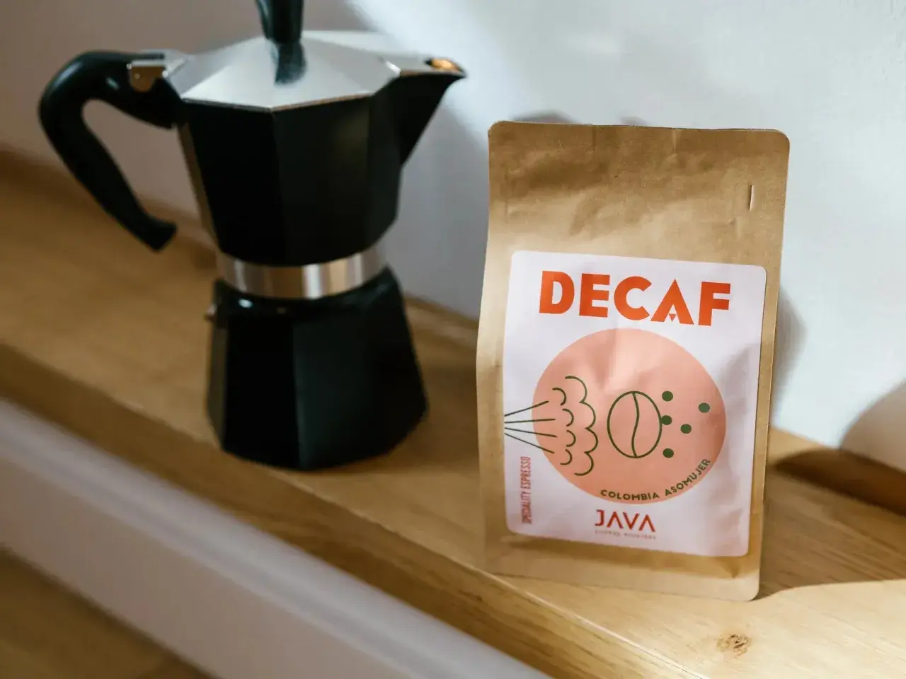Czarna kawiarka i paczka kawy bezkofeinowej "DECAF" od JAVA Coffee Roasters. Idealny zestaw na poranną kawę z kawiarki.