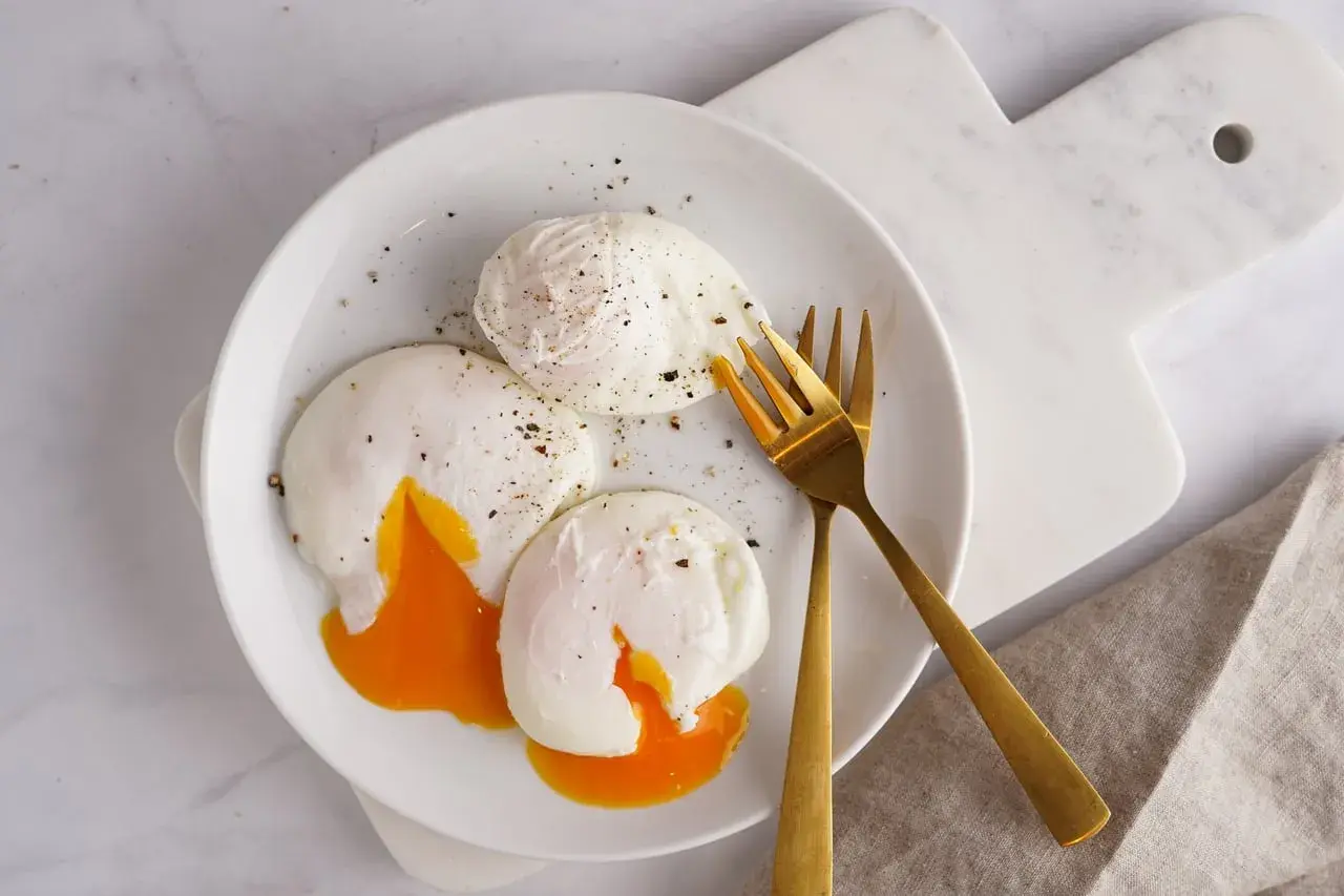 Trois œufs pochés parfaits, avec leurs jaunes coulants, assaisonnés de poivre noir. Un délice de différents types d'œufs pour un petit-déjeuner gourmand.