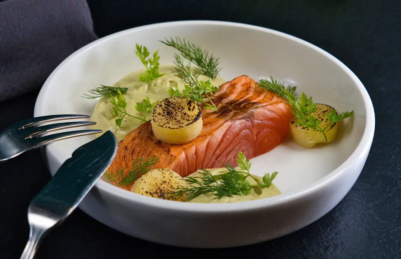 Un délicieux saumon à la toscane, servi avec une sauce crémeuse, des pommes de terre grillées et des herbes fraîches.