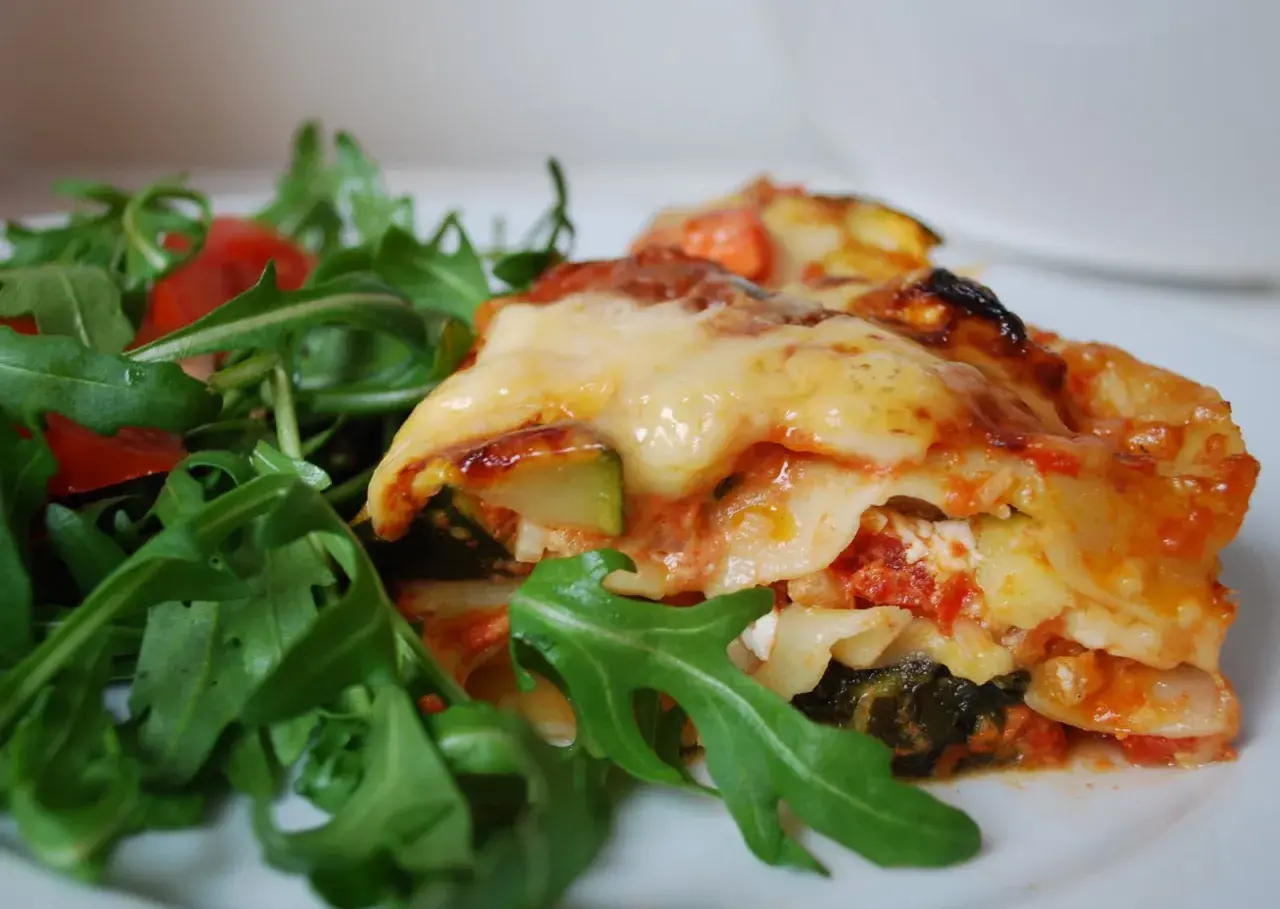 En bit krämig grönsakslasagne med ruccolasallad, perfekt för en vegetarisk recept topplista.