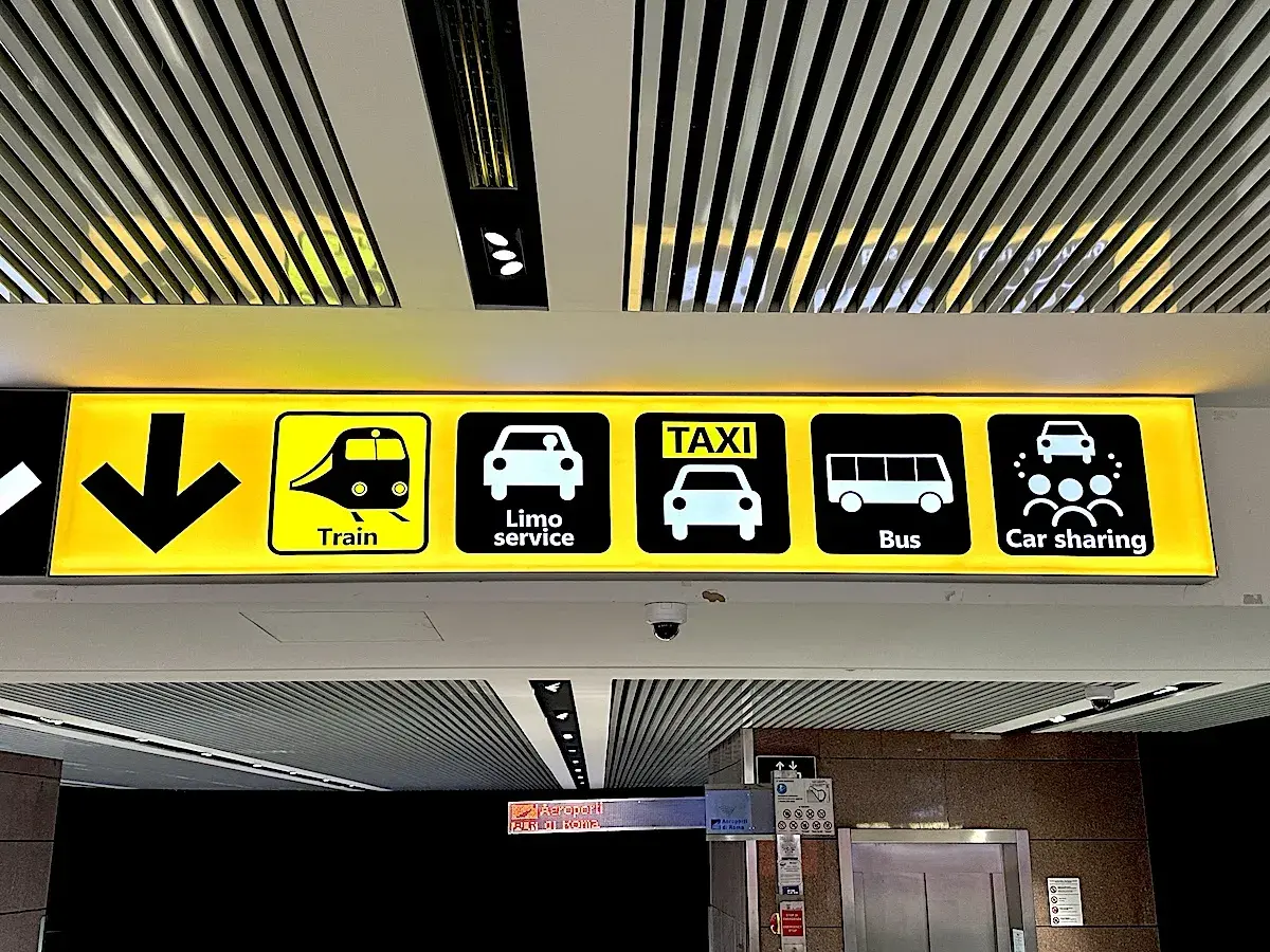Znaki transportu na lotnisku Rzym Fiumicino: pociąg, limuzyna, taksówka, autobus, car sharing.