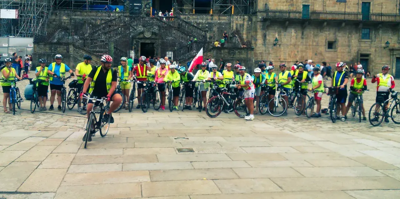 Grupa rowerzystów w kamizelkach odblaskowych przed katedrą. Szukasz najlepszych tras pielgrzymkowych w Polsce dla rowerzystów?